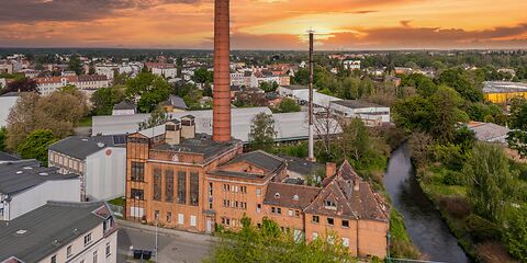 Das frühere Kraftwerk Avellis mit einem großen Schornstein bei Sonnenuntergang.