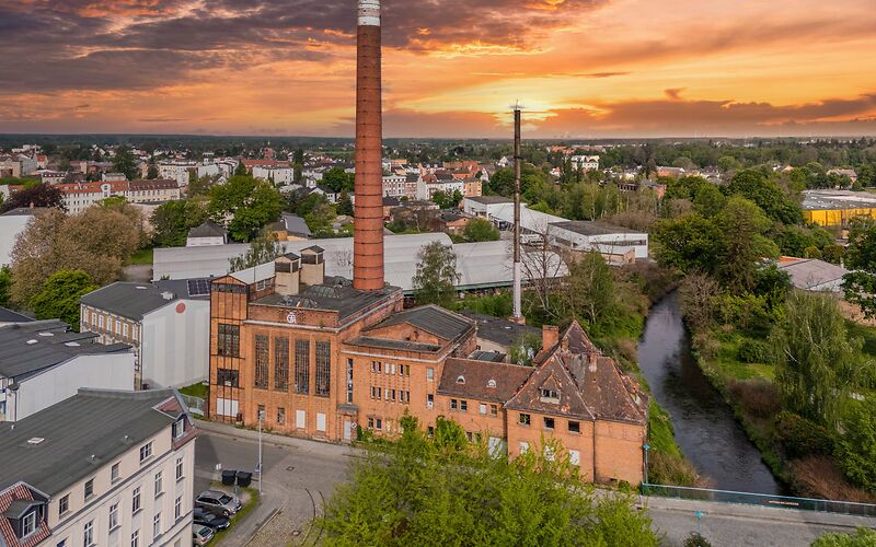 Das frühere Kraftwerk Avellis mit einem großen Schornstein bei Sonnenuntergang.