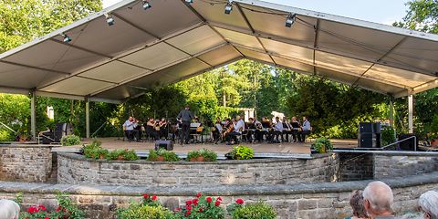 Blick auf die Schillerbühne im Vordergrund Zuschauer mit Blick auf die Bühne, auf der ein Orchester spielt