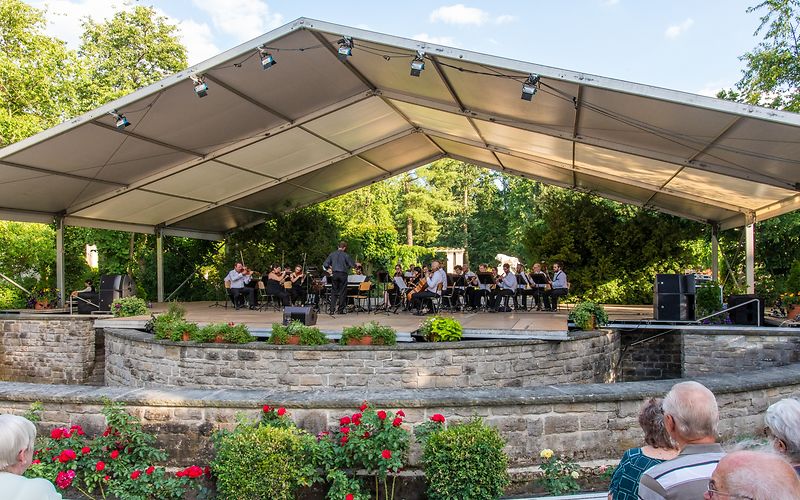 Blick auf die Schillerbühne im Vordergrund Zuschauer mit Blick auf die Bühne, auf der ein Orchester spielt