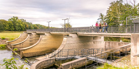 Familie steht auf der Brücke der Wehranlage und schaut auf die Fischtreppe