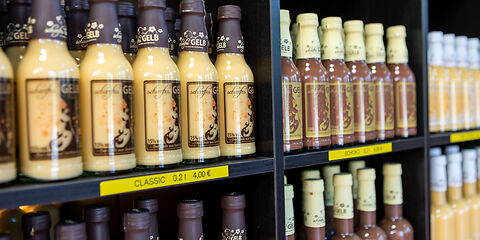 Mehrere bunte Flaschen Eierlikör der Firma scharfesGELB nebeneinander aufgereiht. Die Etiketten sind farbig und unterschiedlich gestaltet.