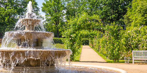 Im Vordergrund Kaskadenbrunnen und rechts im Hintergrund ein Rosenbogen