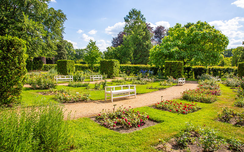 Garten der prämierten Schönheiten mit kleinen Rosenbeeten und eine weiße Parkbank