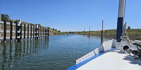 Eine Schifffahrt durch den Ilse-Kanal. Das Schiff fährt aus einem Tunnel auf das Wasser hinaus. Links und rechts des Kanals stehen grüne und rote Pfähle.