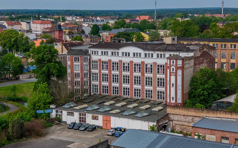 Auf dem Foto ist eine große Fabrik zu sehen, der frühere Sitz der Firma Hänsel & Co. Das Gebäude ist dreietagig. Die Fassade besteht aus weißen und dunkelroten Brandziegeln.