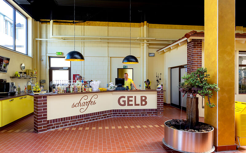 Die Eierlikörbar ‚scharfesGELB‘ mit der Kasse. Die Verkostung für individuelle Gäste findet hier statt. Die Einrichtung ist in Gelb, Braun und Schwarz gehalten.
