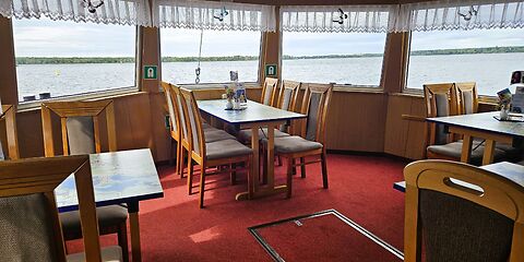 Im Unterdeck des Fahrgastschiffes „Santa Barbara“ befinden sich gemütliche Sitzplätze mit einem schönen Blick durch die Fenster auf den Senftenberger See. Die Tischplatten zeigen Karten des Lausitzer Seenlandes, auf denen die Seen und die Umgebung dargestellt sind.