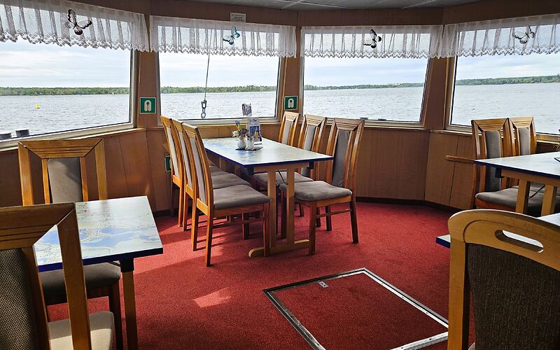 Im Unterdeck des Fahrgastschiffes „Santa Barbara“ befinden sich gemütliche Sitzplätze mit einem schönen Blick durch die Fenster auf den Senftenberger See. Die Tischplatten zeigen Karten des Lausitzer Seenlandes, auf denen die Seen und die Umgebung dargestellt sind.