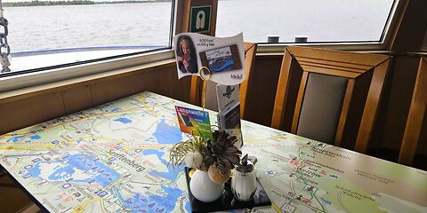 Zu sehen ist eine touristische Karte des Lausitzer Seenlandes, die als Tischplatte auf dem Fahrgastschiff „Santa Barbara“ dient. Die Karte zeigt die Seen der Region sowie zahlreiche touristische Attraktionen und Ausflugsziele.