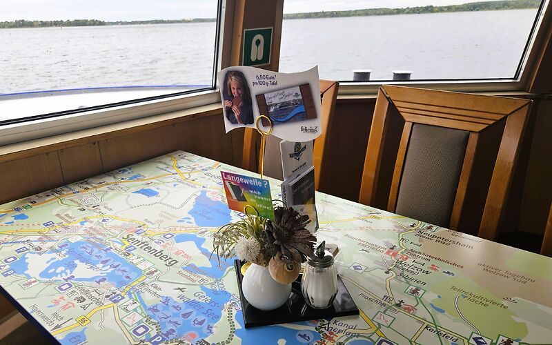 Zu sehen ist eine touristische Karte des Lausitzer Seenlandes, die als Tischplatte auf dem Fahrgastschiff „Santa Barbara“ dient. Die Karte zeigt die Seen der Region sowie zahlreiche touristische Attraktionen und Ausflugsziele.