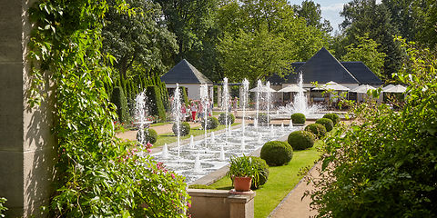 Große Wasserspiele zeigen Wasserfontänen, im Hintergrund Cafe