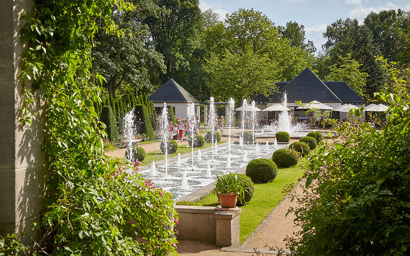 Große Wasserspiele zeigen Wasserfontänen, im Hintergrund Cafe