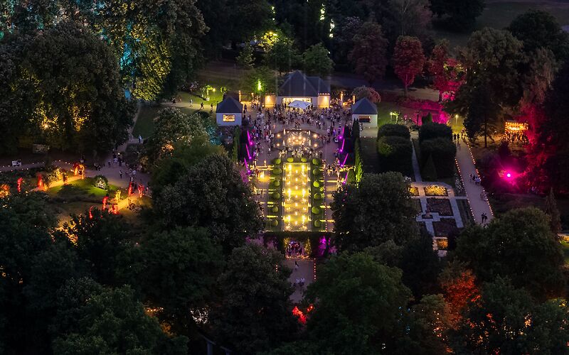 Blick von oben auf den Rosengarten in Forst bei Nacht – farbenfrohe Lichtilluminationen während der Rosengartenfesttagen leuchten thematische Gartenbereiche aus.