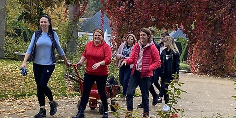 Gruppe mit Handwagen gehen durch den herbstlichen Park