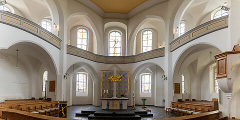 Auf dem Foto ist der helle Innenraum der Stadtkirche St. Nikolai in Forst (Lausitz) zu sehen. Große Fenster lassen viel Licht in den Kirchenraum. Im Altarbereich befindet sich eine schlichte, moderne Altargestaltung. 