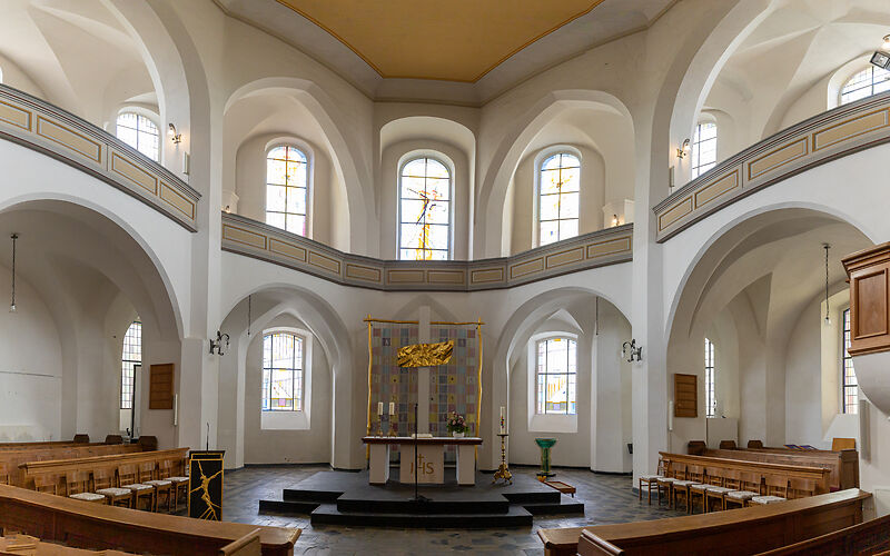 Auf dem Foto ist der helle Innenraum der Stadtkirche St. Nikolai in Forst (Lausitz) zu sehen. Große Fenster lassen viel Licht in den Kirchenraum. Im Altarbereich befindet sich eine schlichte, moderne Altargestaltung. 