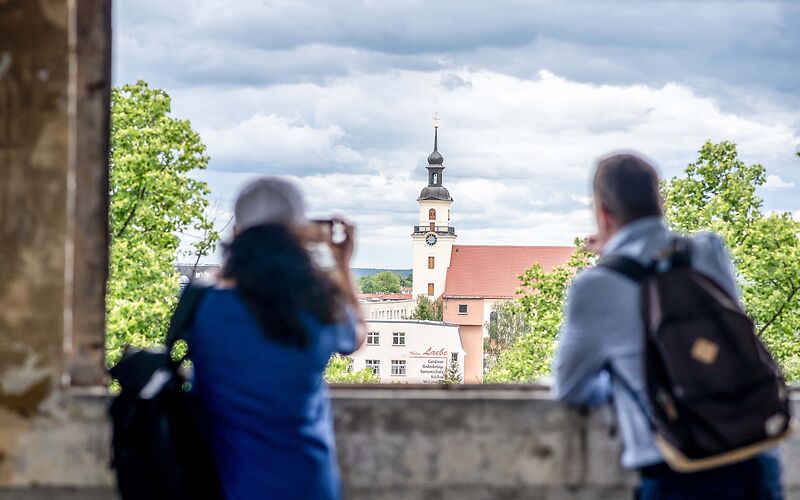 Eine Frau und ein Mann schauen sich die St. Nikolaikirche vom Fenster der Gründer- und Traumfabrik in Forst (Lausitz) an.