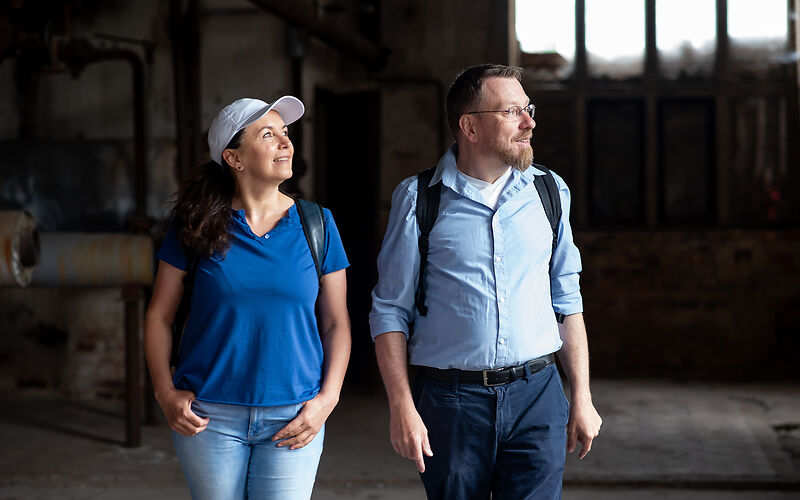 Zwei Personen, eine Frau und ein Mann, besichtigen eine alte Halle der Gründer- und Traumfabrik in Forst (Lausitz).