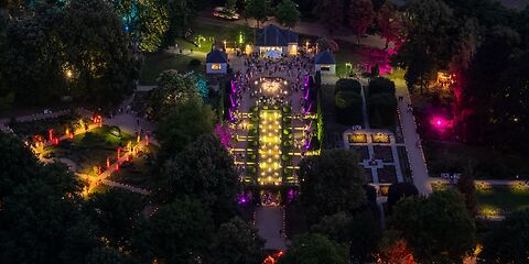 Luftbild auf den mit bunten Lichtern erleuchteten Rosengarten bei Dunkelheit.