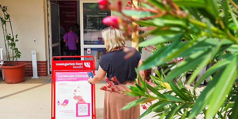Am Besucherzentrum scannt eine Person den QR Code am Aufsteller