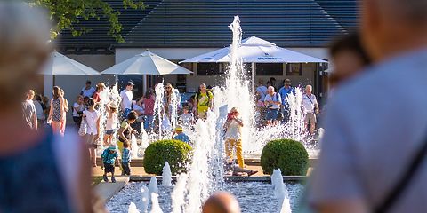 Menschen stehen und sitzen an den großen Wasserpielen 
