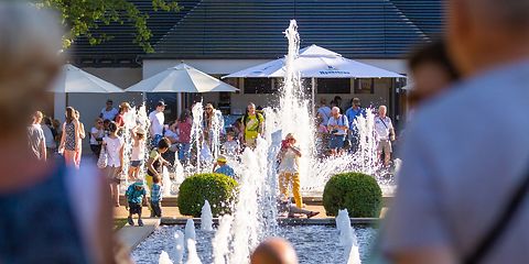 Menschen stehen und sitzen an den großen Wasserpielen 