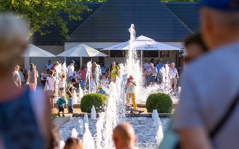 Menschen stehen und sitzen an den großen Wasserpielen 