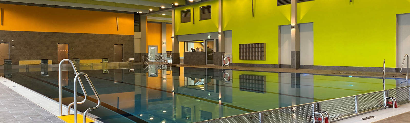 Fotograf: Jullian Arzt, Bildrechte: Stadt Forst (Lausitz) Blick auf ein 5-bahniges Schwimmbecken mit Ein- und Austeigen an den Seiten (hinten eine Treppe und zwei Leitern). Die Wand rechts ist grün gestrichen, die Wand links ist unten dunkelbraun und oben orange.