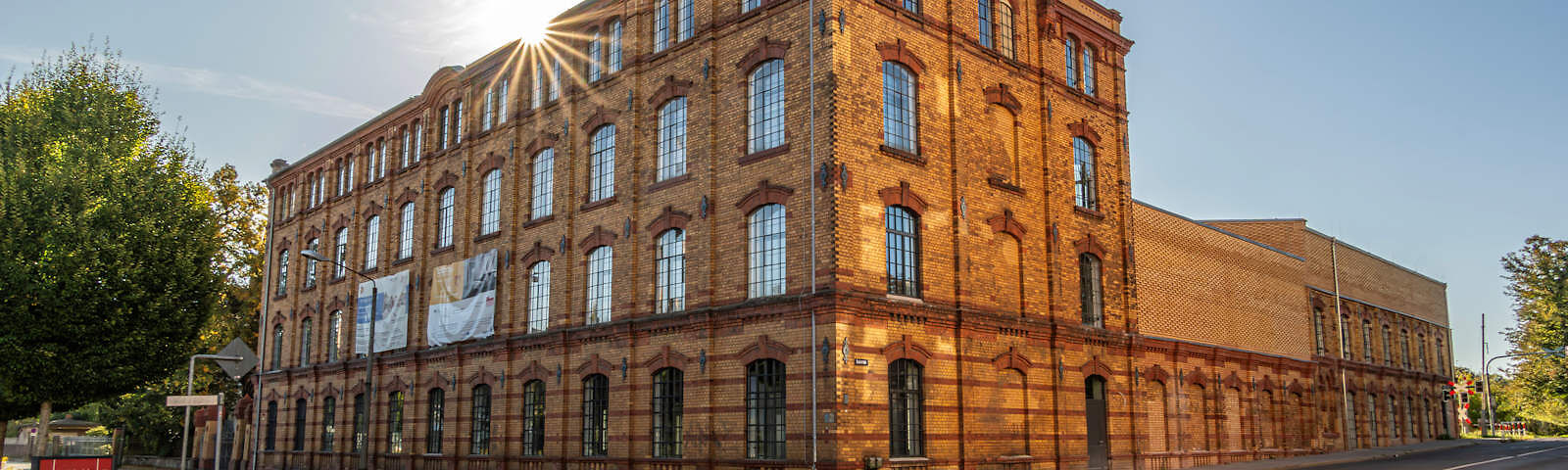 Der linke Teil des Museums ist ein aus Steinen gemauertes Gebäude mit 4 Fensterreihen übereinander. An diesen Gebäude sind rechts zwei niedrigere Gebäudeteile angeschlossen, der mittlere Teil ist fensterlos. Die Sonne scheint und der Himmel ist wolkenlos.